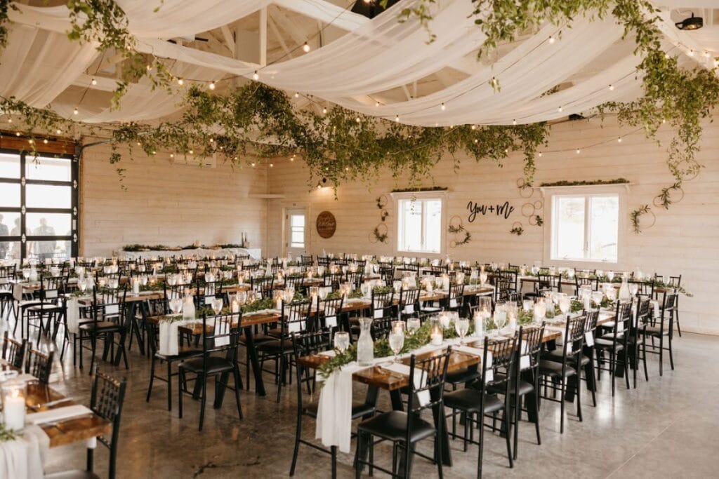 White Barn with Table Decor, Cafe Lighting, and Greenery on the Ceiling
