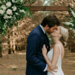Maidenwood-events-and-weddings-bride-and-groom-kiss-in-front-of floral-arch